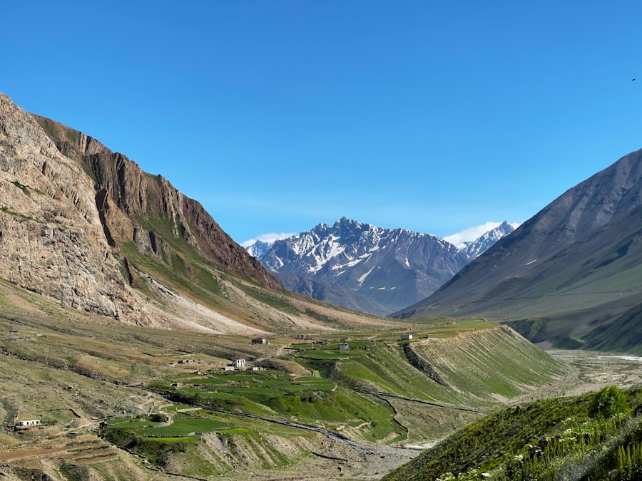 A green terraced Himalayan valley with a village below a snow-capped ridge
