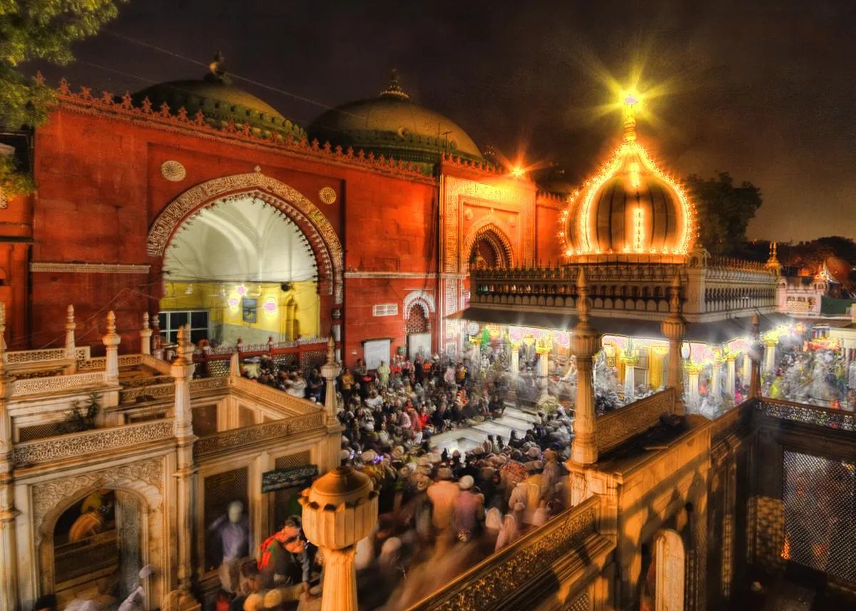 A dargah courtyard lit up and crowded at night