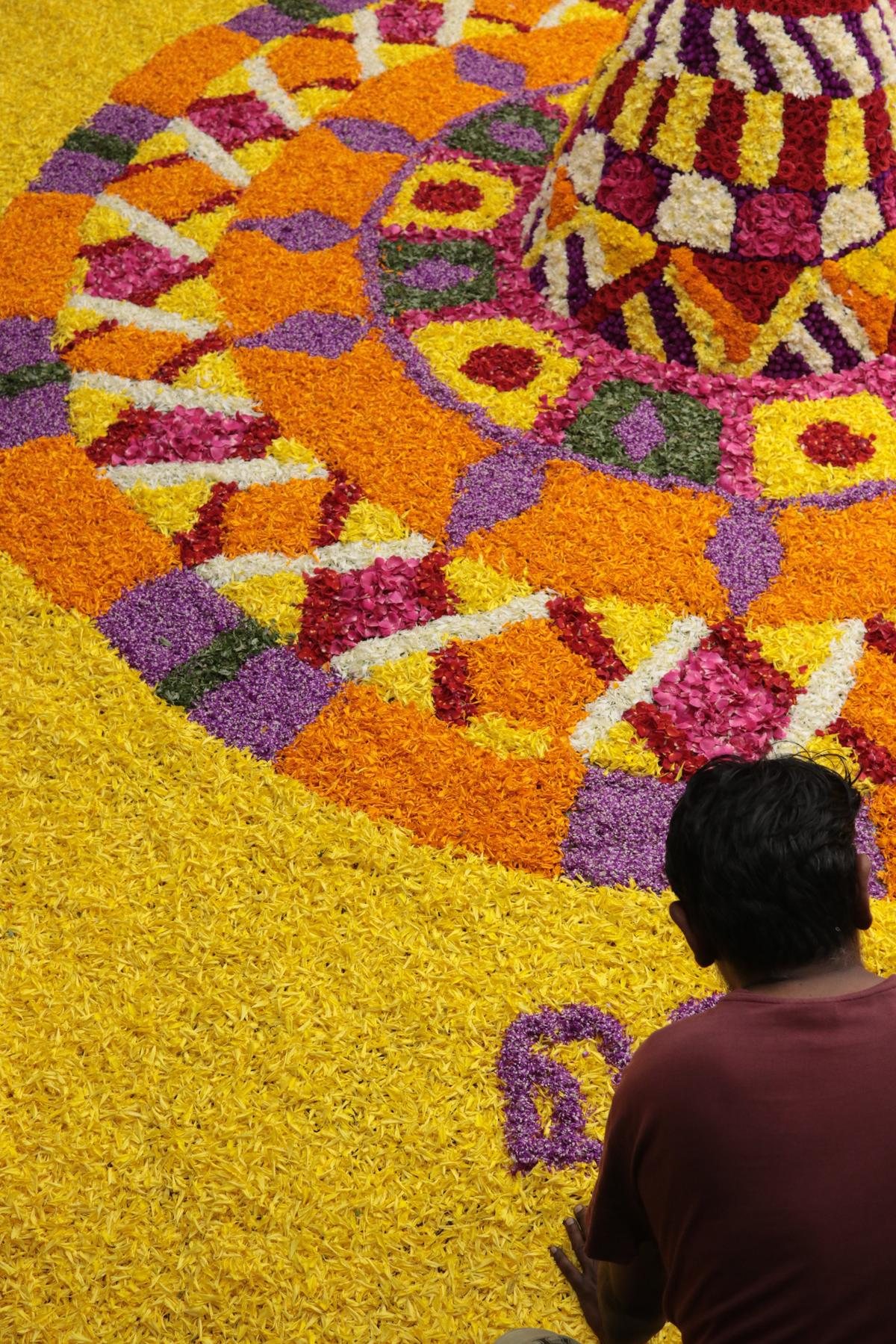 An Onam pookalam flower carpet being laid out