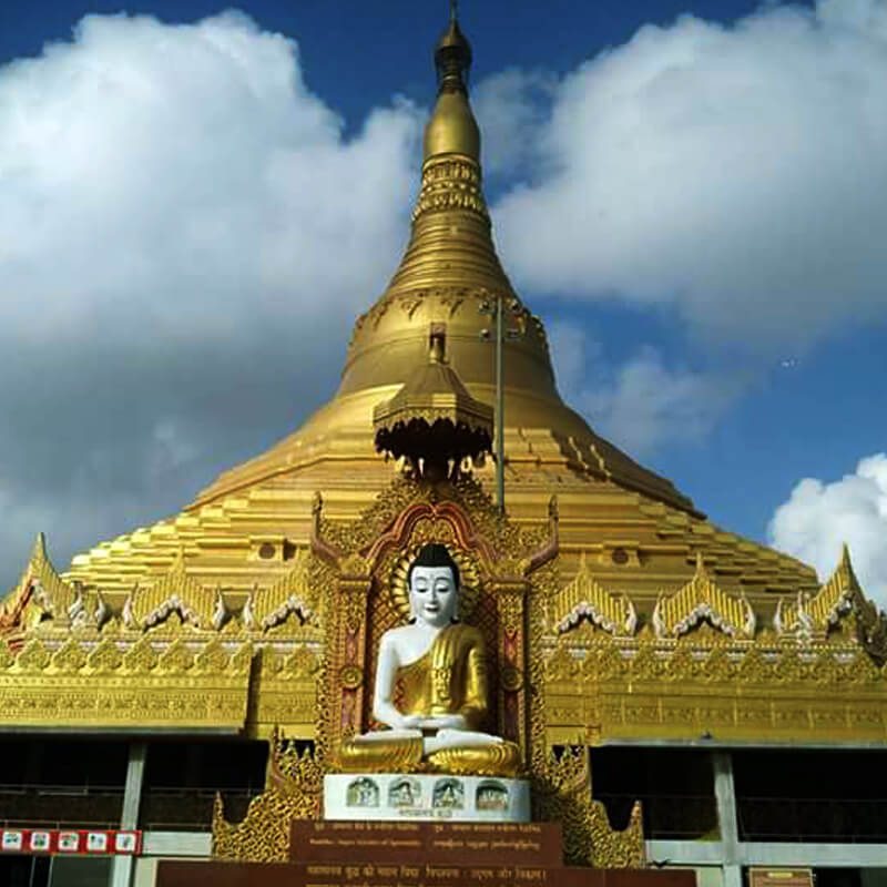 A golden Vipassana meditation pagoda under monsoon cloud