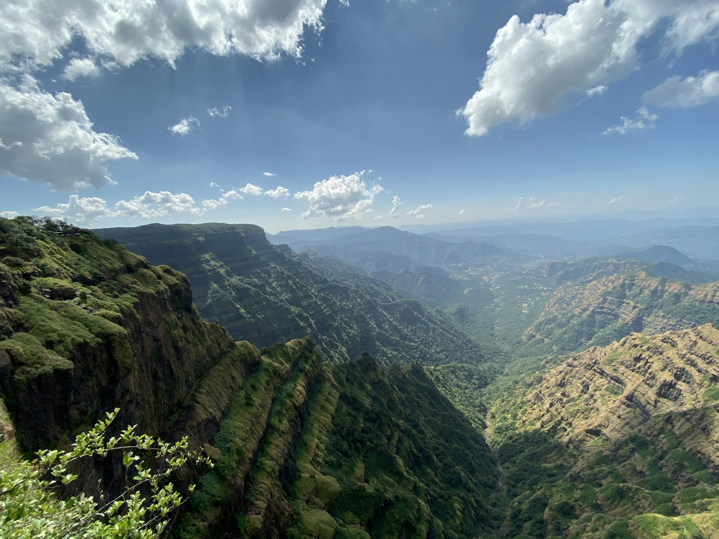 The Sahyadri escarpment seen from a tableland edge, flat basalt ridges dropping to a hazy valley.